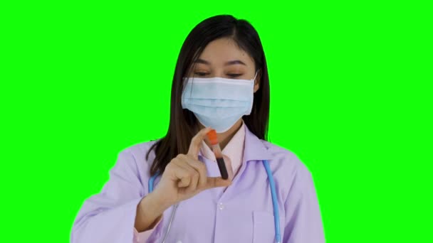 带医疗面罩的女医生在绿色背景下拿着输卵管 — 图库视频影像
