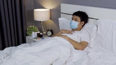 Tıbbi maskeli hasta adam virüs hastalığı ve yatakta ateş, koronavirüs (covid-19) pandemik konsept.