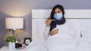 Sıcaklığını ölçmek için termometre kullanan maskeli hasta kadın, koronavirüs (covid-19) pandemik konsept.