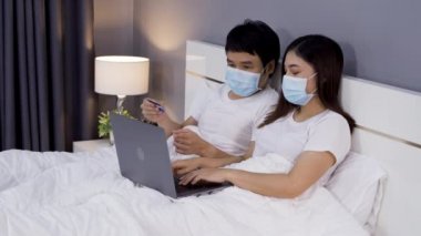 Karantina pandemik koronavirüsü (covid-19) sırasında kredi kartıyla online alışveriş yapmak için dizüstü bilgisayar kullanan çift evde kalıyor..