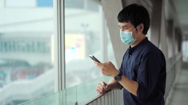 Joven Hombre Asiático Usando Teléfono Inteligente Usando Máscara Médica Para — Vídeos de Stock