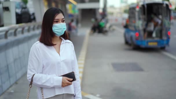 스마트폰을 거리에서 정류장에서 버스를 기다리고 아시아인 여성은 코로나 바이러스 확산을 — 비디오