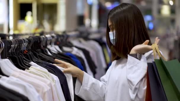 Jonge Vrouw Die Kleding Kiest Het Winkelcentrum Haar Medische Masker — Stockvideo