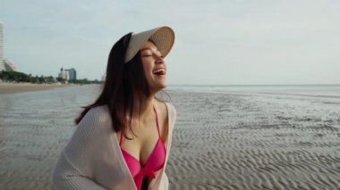 Yavaş çekimde bikinili neşeli kadın deniz sahilinde eğleniyor.