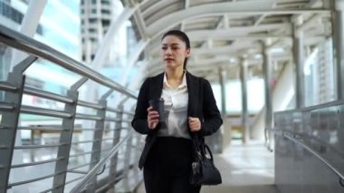 Kadın elinde bir fincan kahveyle şehirde yürüyor.