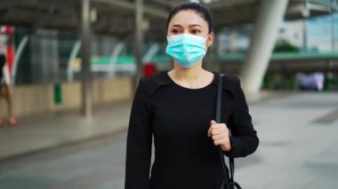 Şehirdeki Coronavirus (covid-19) salgınından korunmak için yürüyen ve tıbbi maske takan iş kadınlarının yavaş çekimleri