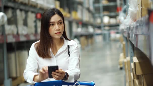 女人在仓库里看她的手机和购物 — 图库视频影像