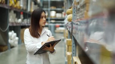 Depoda pano tutan ve envanteri kontrol eden genç bir kadın.