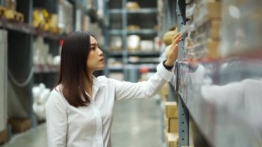 Depodaki envanteri kontrol eden genç bir kadın işçi.