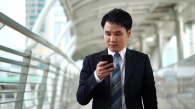 Şehirde yürüyen ve akıllı telefon kullanan bir iş adamı.