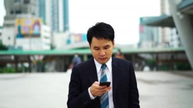 Şehirde yürüyen ve akıllı telefon kullanan bir iş adamı.