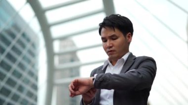 İş adamı şehirdeki saatini kontrol ediyor.