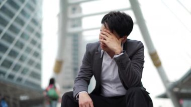 Stresli bir iş adamı şehirde yerde oturuyor. 