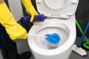 Ellerinde eldivenlerle banyoda klozet temizlerken.