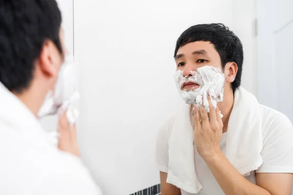 Jovem Aplicando Creme Espuma Rosto Antes Fazer Barba Espelho Banheiro — Fotografia de Stock