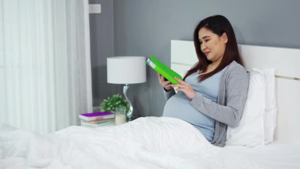 Gravid Kvinna Läser Bok Säng — Stockvideo