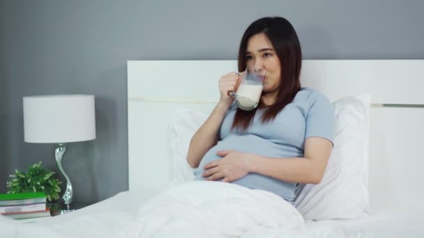 Schwangere Trinkt Milch Auf Einem Bett — Stockvideo