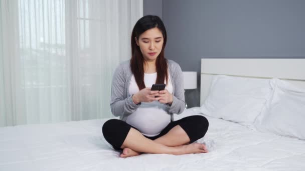 Zwangere Vrouw Met Smartphone Een Bed — Stockvideo