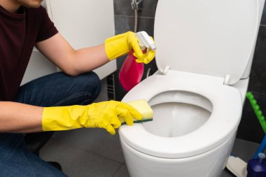 Genç adam tuvalette klozet temizliyor.