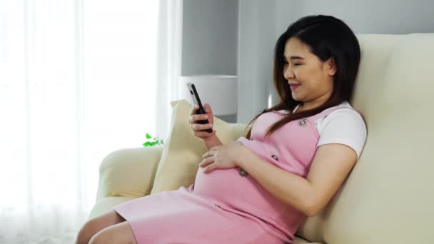 Femme Enceinte Utilisant Smartphone Sur Canapé Dans Salon — Video