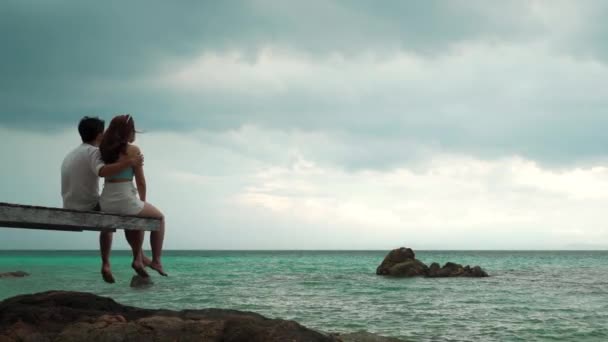 Ευτυχισμένο Νεαρό Ζευγάρι Κάθεται Ξύλινη Γέφυρα Και Παραλία Στη Θάλασσα — Αρχείο Βίντεο