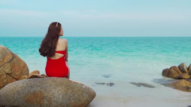 水着姿の若い女性がタイのラヨーン島コ ムノルク島の海と石のビーチに座って — ストック動画