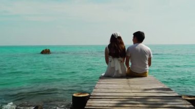 Koh MunNork Adası, Rayong, Tayland 'daki ağaç köprü ve deniz sahillerinde oturan mutlu genç çift.