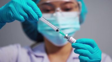 Kadın doktor Coronavirus (Covid-19) aşı şişesini şırınga ilacına çiziyor