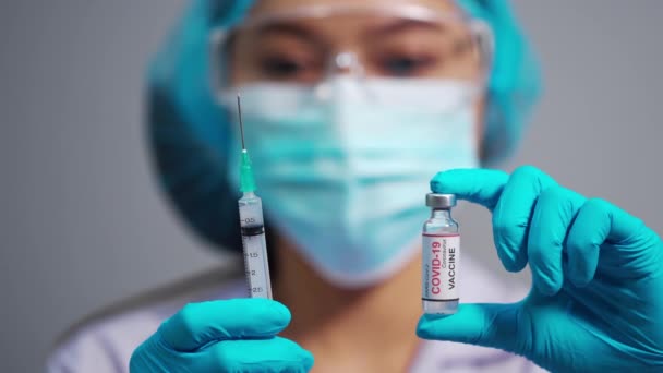 コロナウイルス Covid ワクチンボトルと注射器の注射薬を保持する女性医師 — ストック動画