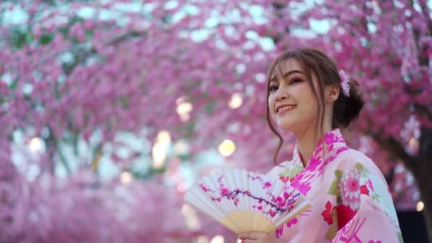 Γυναίκα Yukata Κιμονό Φόρεμα Εκμετάλλευση Πτυσσόμενο Ανεμιστήρα Και Αναζητούν Λουλούδι — Αρχείο Βίντεο