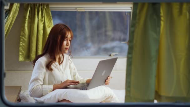 一名年轻女子在一辆野营的Rv面包车的床上用笔记本电脑 — 图库视频影像