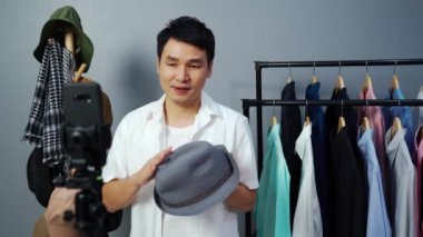 Genç adam internette şapka ve giysi satıyor akıllı telefondan canlı yayın, iş dünyasında e-ticaret yapıyor.