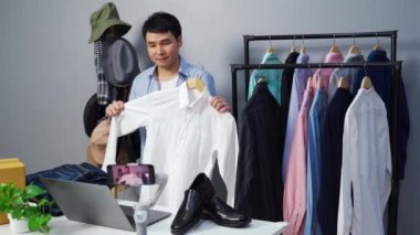 Genç adam online kıyafet ve aksesuar satıyor akıllı telefonuyla canlı yayın, iş dünyasında e-ticaret yapıyor.
