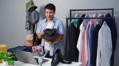 Genç adam internette şapka ve giysi satıyor akıllı telefondan canlı yayın, iş dünyasında e-ticaret yapıyor.