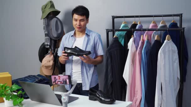 若い男が靴や服をオンラインで販売するスマートフォンライブストリーミング 自宅でビジネスオンライン電子商取引 — ストック動画