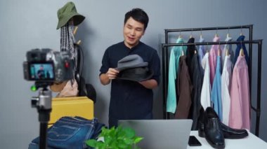 Genç adam çevrimiçi şapka ve giysi satıyor. Kamerayla canlı yayın, iş dünyası evde e-ticaret yapıyor.