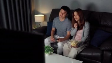 Genç çift geceleri kanepede film seyrediyor.