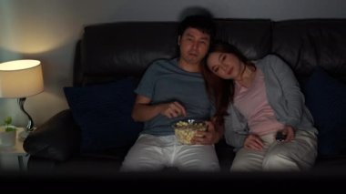 Genç çift geceleri kanepede film seyrediyor.