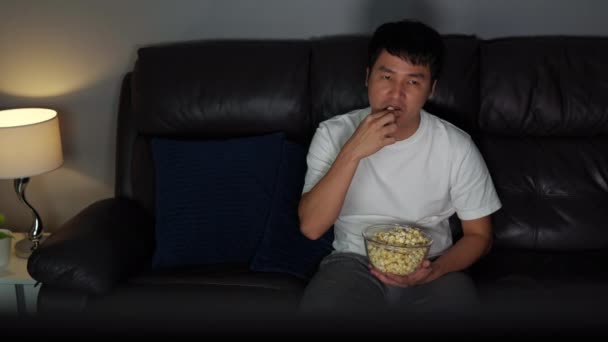 Junger Mann Schaut Fern Und Isst Nachts Popcorn Auf Dem — Stockvideo
