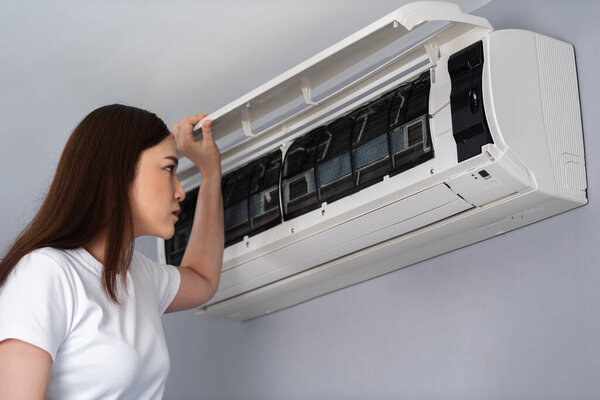 young woman open the air conditioner indoor at home