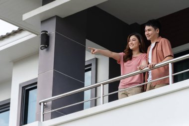 happy couple relaxing and looking from balcony of home