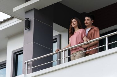 happy couple relaxing and looking from balcony of home