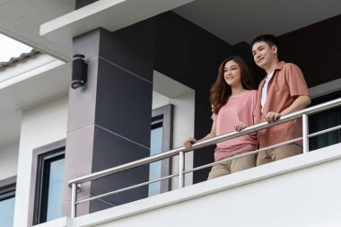 happy couple relaxing and looking from balcony of home