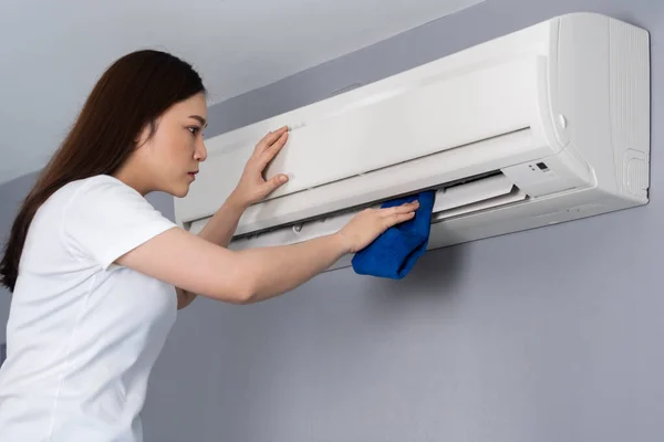 Jonge Vrouw Schoonmaken Van Airconditioner Met Doek Thuis — Stockfoto