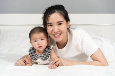 Mutlu anne ve bebek evde bir yatakta yatıyor.