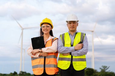 young engineer team working against wind turbine farm