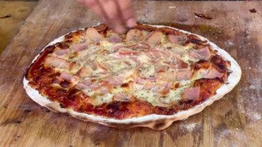 Eller kekik serpiştirir ve ev yapımı kömürlü pizza keser.