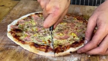 Yavaş çekimde mangal kömürlü pizzayı kesiyor.
