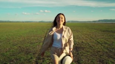 Yavaş çekim neşeli kadın yeşil alanda güneş ışığıyla yürüyor.