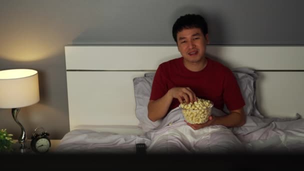 Fiatal Férfi Néz Eszik Popcorn Ágyon Éjszaka — Stock videók